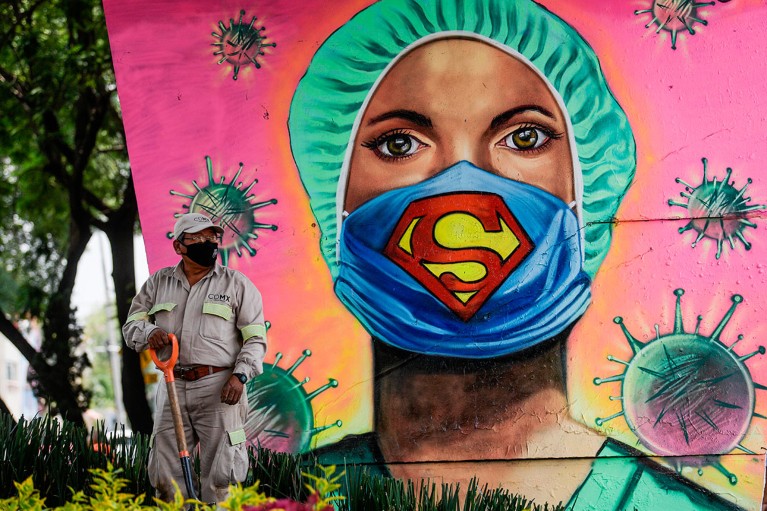 A city gardener works next to a mural showing a health worker wearing a face mask in Mexico City.