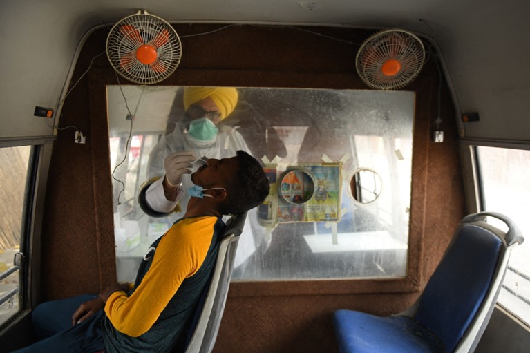A health worker collects a nasal swab sample from a man in a mobile testing van