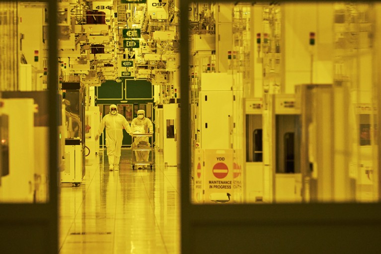 Technicians push a cart in the cleanroom at Fab7 in the Globalfoundries Inc. semiconductor fabrication facility