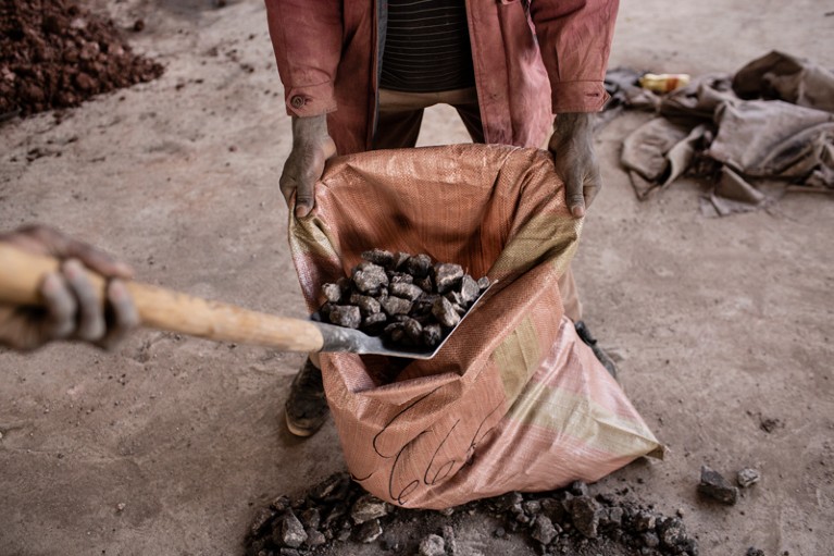 A miner filling a bag with cobalt