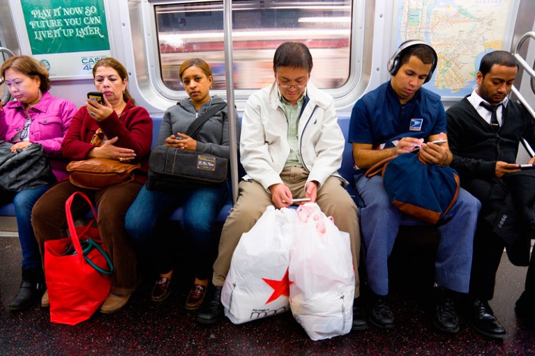 Seated passengers on the subway using their mobile phones