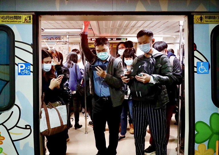 Riders wear masks and look at cell phones while on the Taipei City, Taiwan train