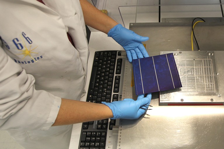 A technician handles a cell at the 1366 Technologies solar manufacturing demonstration plant