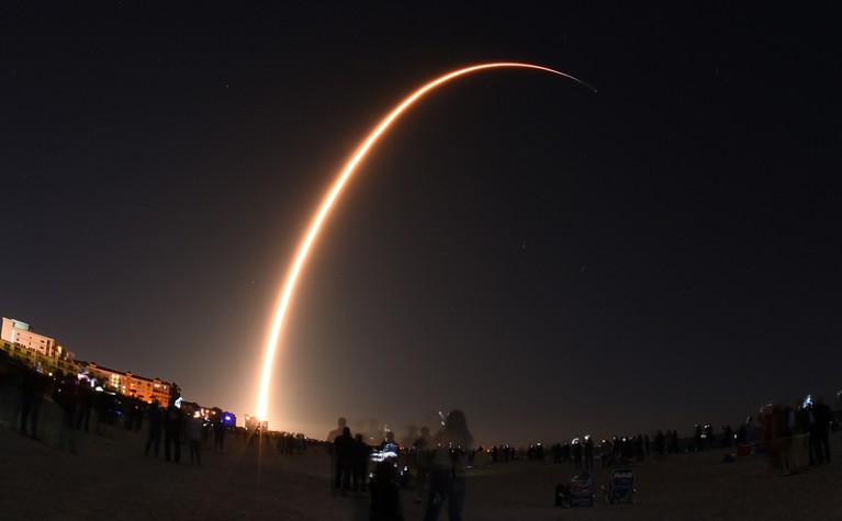 A long exposure of a SpaceX Falcon 9 rocket launch arcing through the night sky
