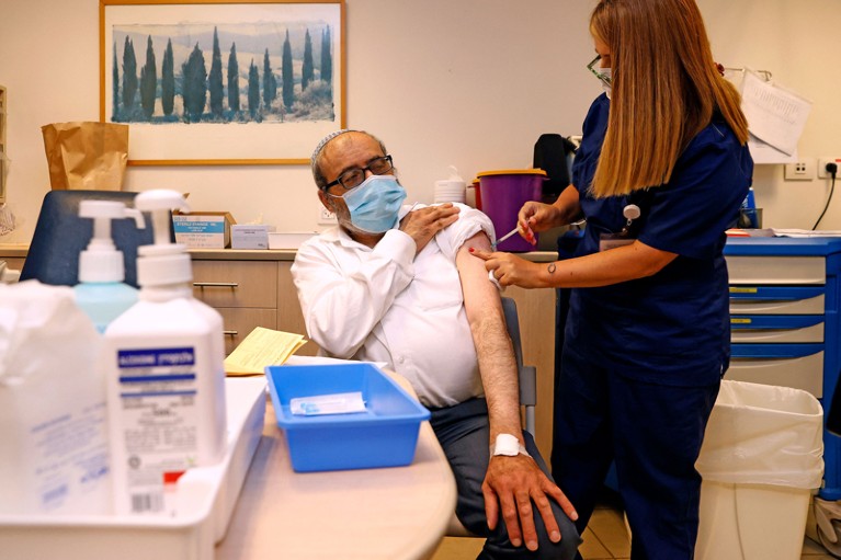 A man receives a dose of the coronavirus vaccine from a nurse in a hospital