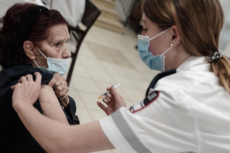 A paramedic delivers a 3rd BioNTech Pfizer booster vaccine to an elderly person