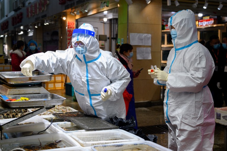 Health officers wearing personal protective equipment collect COVID-19 coronavirus test samples at a fresh market in China