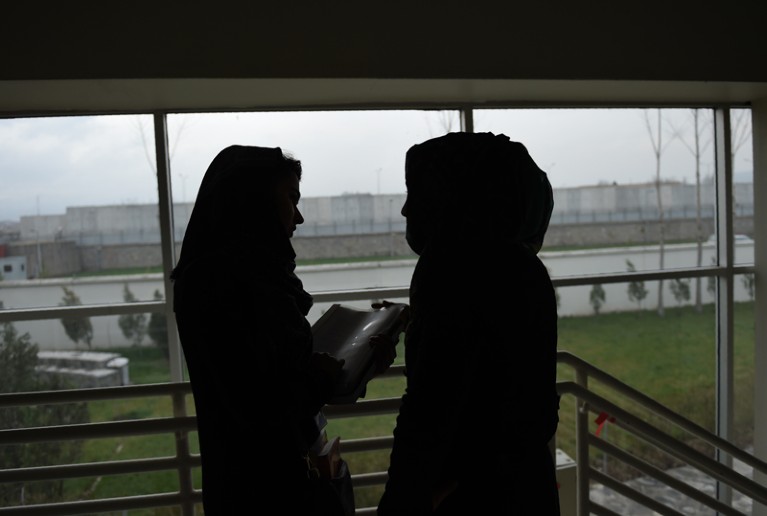 Two silhouetted Afghan students talk in the American University of Afghanistan