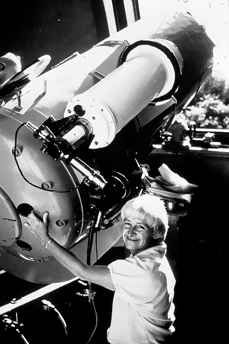 Black and white photo of Carolyn SHoemaker standing nest to a telescope in 1985