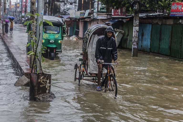 A man cycles through flooded streets in Chattogram, Bangladesh