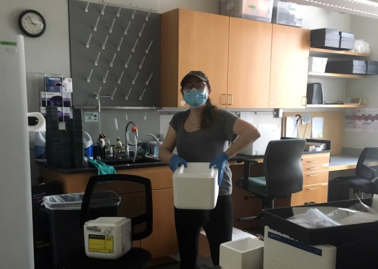 A woman in a mask packs laboratory samples into styrofoam boxes.