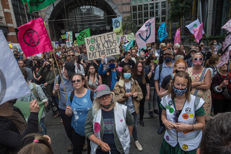Extinction rebellion supporters march with drums, megaphones and banners through London's financial district
