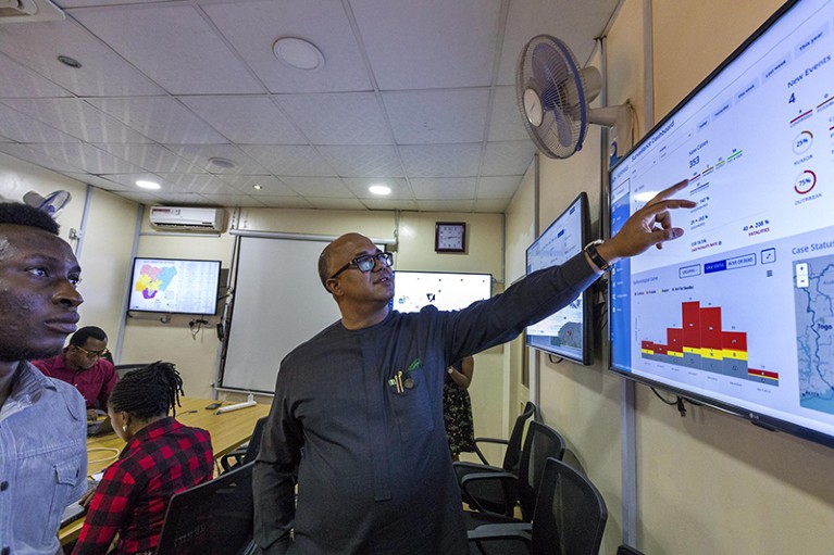 Chikwe Ihekweazu, the leader of the The Nigeria Centre for Disease Control, in his lab explaining a monitor.