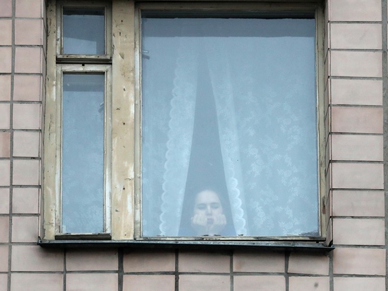 A young woman looks through a window of the quarantined building housing educational premises and dormitory in St Petersburg.
