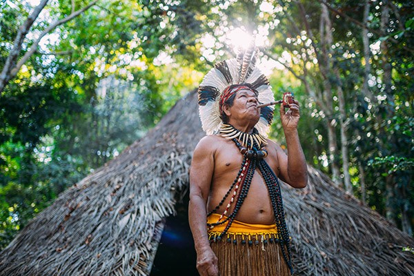 Shaman of the Pataxó tribe, wearing feather headdress and smoking a pipe.