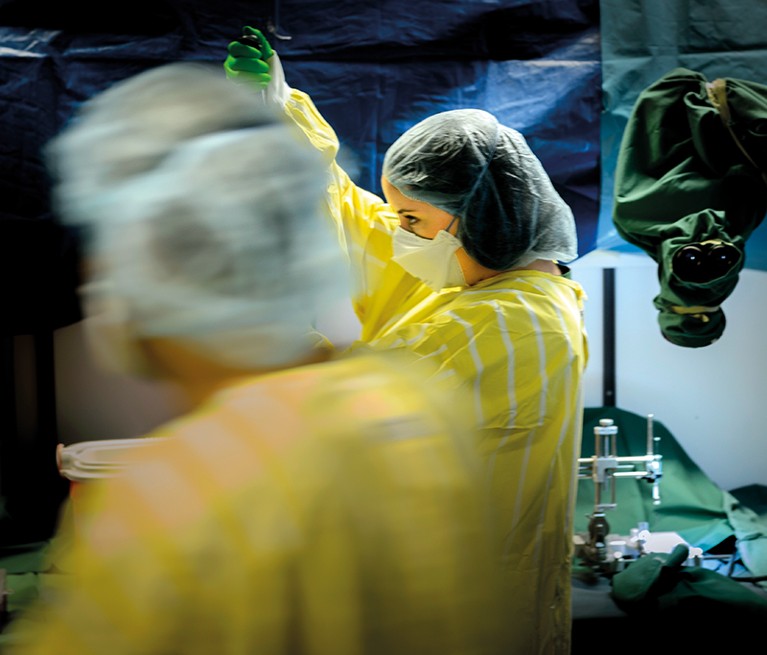 Two researchers in surgical gowns and masks stand in an operating theatre
