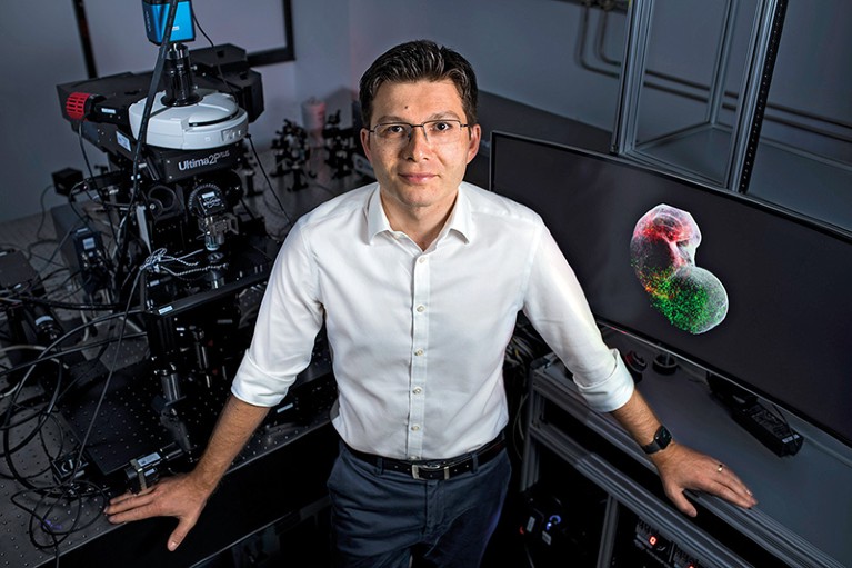 Sergiu Pașca stands in front of imaging equipment in a lab
