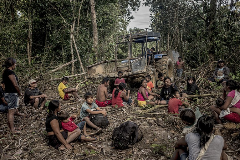 People take a break in front of equipment used to illegally mine their land in Brazil's Amazon.