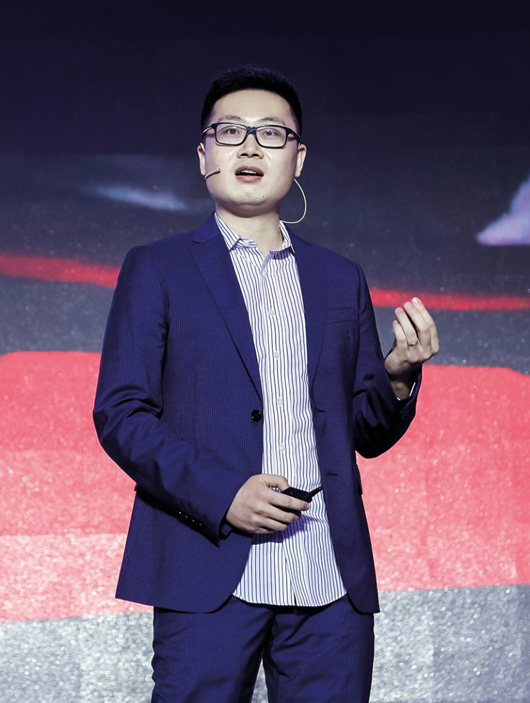 Xinge Yu stands on stage giving a talk