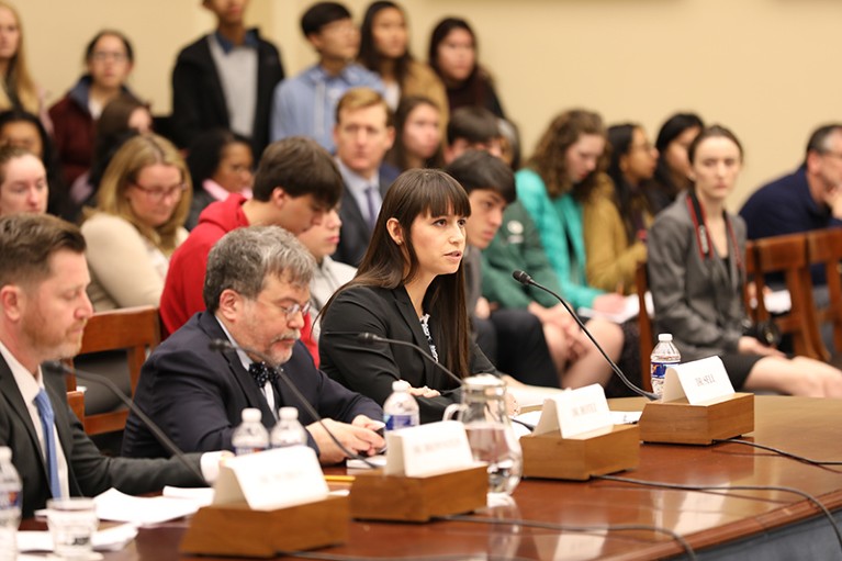 Tara Kirk Sell, surrounded by people and press, at her Congressional testimony.