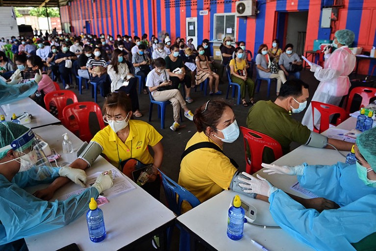 Nhân viên y tế kiểm tra sức khỏe người dân trước khi tiêm các liều vắc xin CoronaVac hoặc AstraZeneca COVID-19 ở Bangkok.