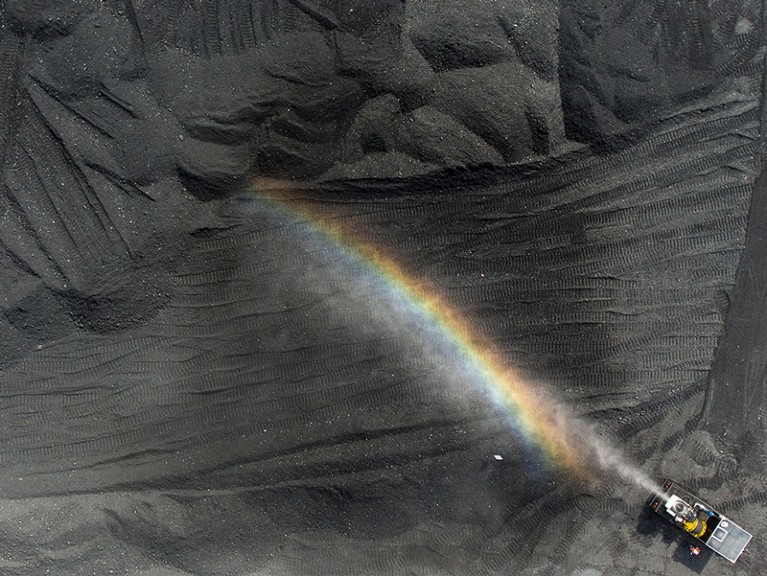 A rainbow forms on water from a spray machine used to suppress coal dust at an open pit coal mine, Russia.