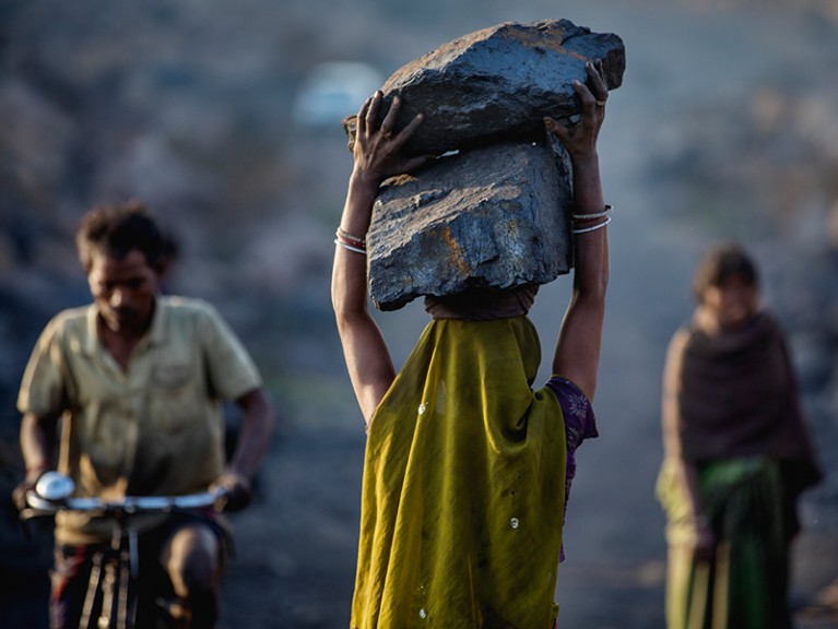 A female worker has piled coal on her head while she is working in Jharia coal field, India.