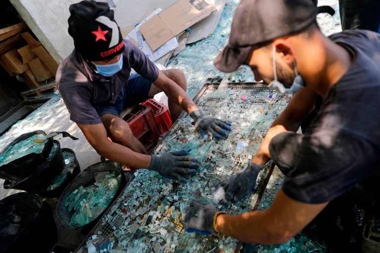 Workers sort through broken glass as a result of the Beirut explosion at factory