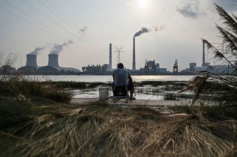 An angler is seen fishing along the Huangpu river across the Wujing Coal-Electricity Power Station in Shanghai.