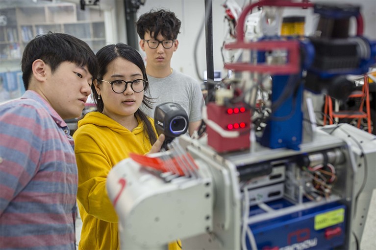 Three students working inside of a research center for humanoid robots at KAIST in South Korea