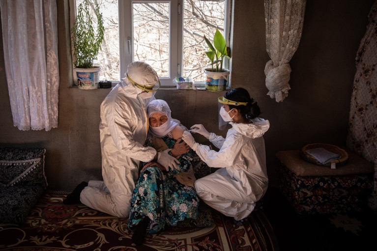 Two nurses vaccinate a 74 year old in her home