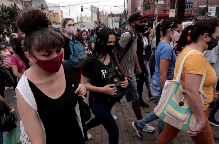People wearing face masks walk the busy shopping streets of downtown Sao Paulo