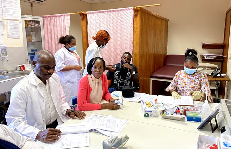 Two doctors and three nurses are pictured at a clinic in Gabon, with the first patient of a clinical trial