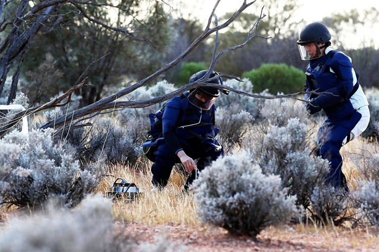 Two members of the Japan Aerospace Exploration Agency are shown retrieving a capsule in Woomera, Australia