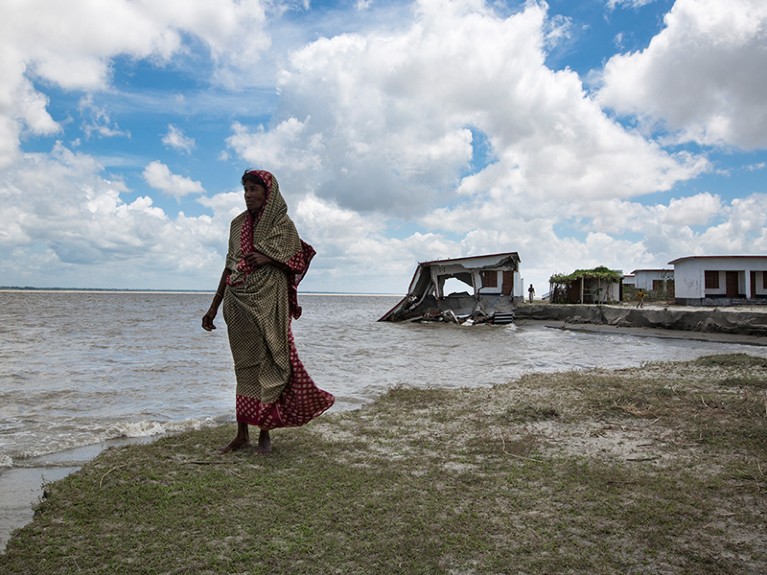 A woman seen near to her eroded shelter home near the Meghna River in Bangladesh.