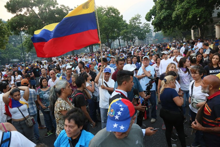 Pro-Guaidó demonstrator holds a flag of Venezuela during clashes with Pro-Government military police officers