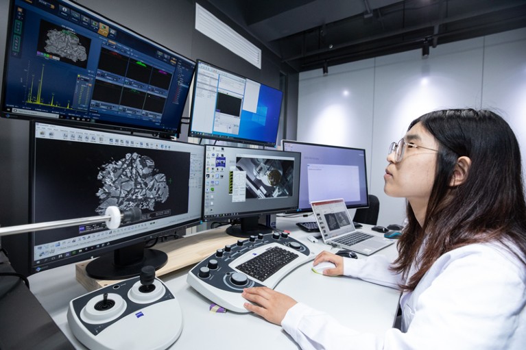 A researchers analyses images of a sample of lunar soil on computer monitors in a lab in Beijing
