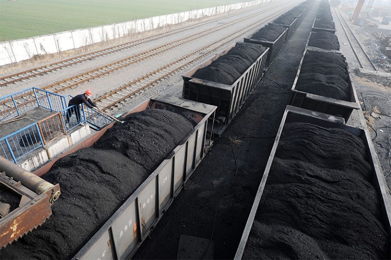 A worker shovels up coal on a freight train at a state-run coal mine in Huaibei, Anhui province, China