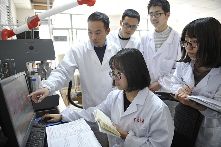 Jie Zeng points to a computer screen, surrounded by four colleagues.