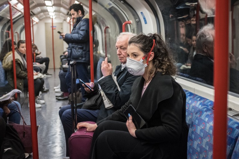 A women riding a busy London underground train carriage is the only passenger wearing a mask