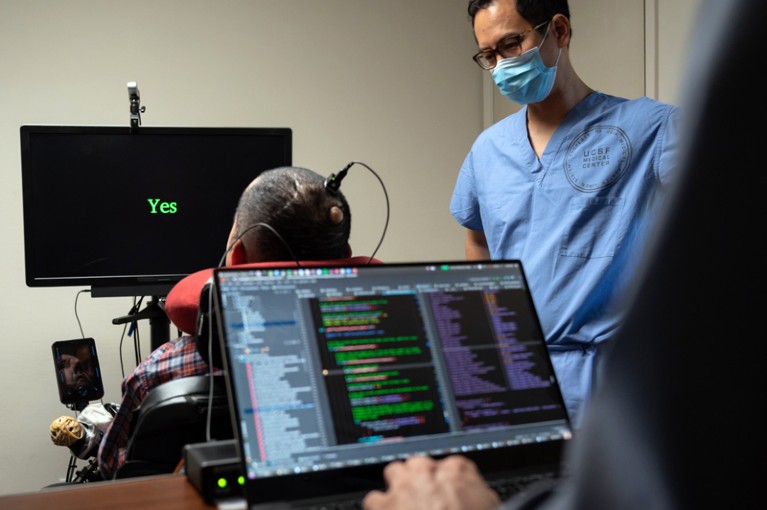 The word 'Yes' appears on a screen as Eddie Chang and a colleague help a paralysed man speak through an implant in his brain