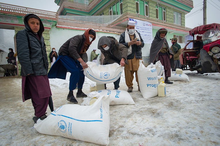 Afghan men transport sacks of flour, as the UN World Food Program (WFP) distributes a critical monthly food ration from USAID.