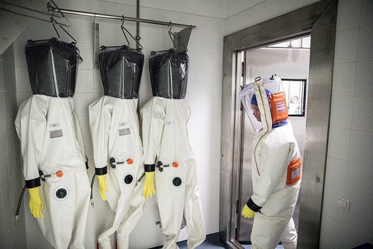 A scientist in a full body protective suit enters the decontamination chamber after working in the biosafety level 4 laboratory.