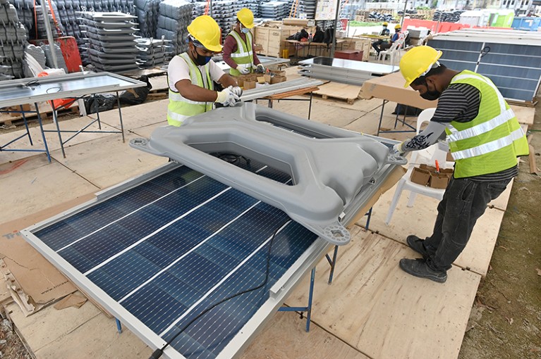 Workers attach a floater onto a solar panel as part of the floating solar power farm on Tengeh reservoir in Singapore.