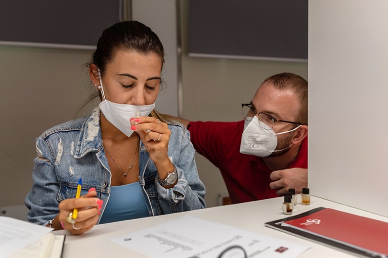 A man who lost his sense of smell after COVID-19 helps a woman recognize smells at a therapeutic workshop in Italy, in 2021.