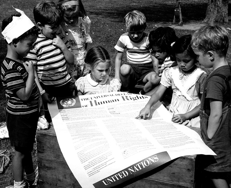 Children of the United Nations International Nursery School looking at a poster of the Universal Declaration of Human Rights.