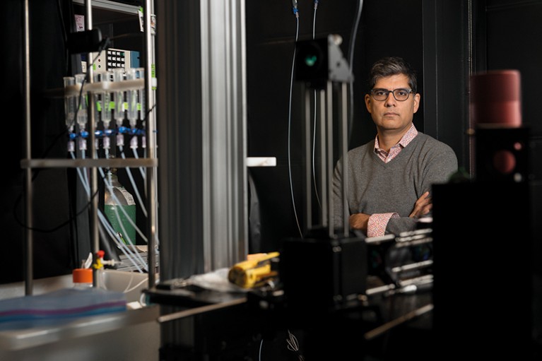 Sandeep Robert Datta stands by a machine with tubes and bottles, which will send smells to mice.
