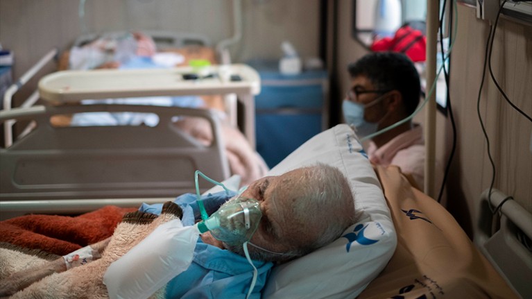 An elderly Iranian man who is infected by COVID-19 uses oxygen as he lies on a hospital bed in a COVID-19 ward in Iran.