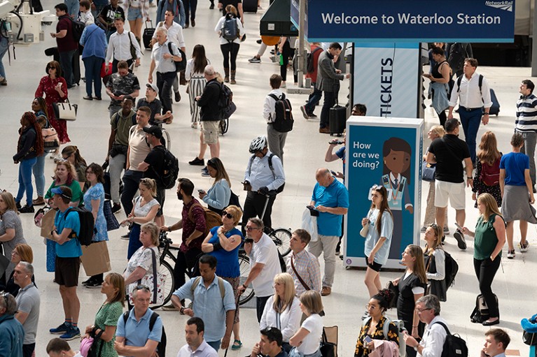 Crowds of rush hour passengers pass through Waterloo train station in London, none wearing masks..