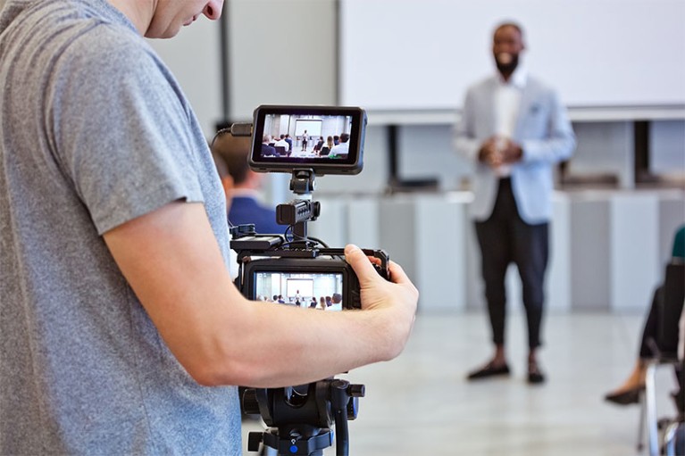 A videographer records someone speaking